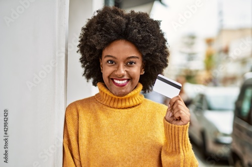 Young african american girl smiling happy holding credit card at the city.