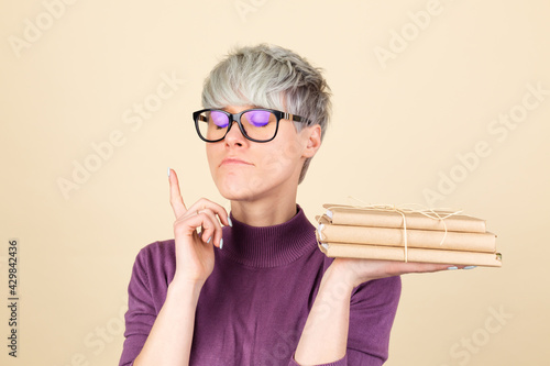 Stylish woman student in purple casual and glasses on beige background thoughtful with closed eyes holding books