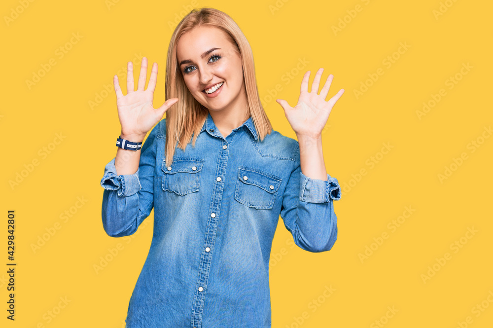 Beautiful caucasian woman wearing casual denim jacket showing and pointing up with fingers number ten while smiling confident and happy. Beautiful caucasian woman wearing casual denim jacket showing and pointing up with fingers number ten while smiling confident and happy.