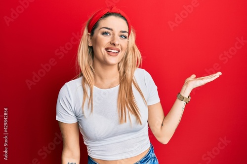 Young caucasian woman wearing casual white t shirt smiling cheerful presenting and pointing with palm of hand looking at the camera. © Krakenimages.com