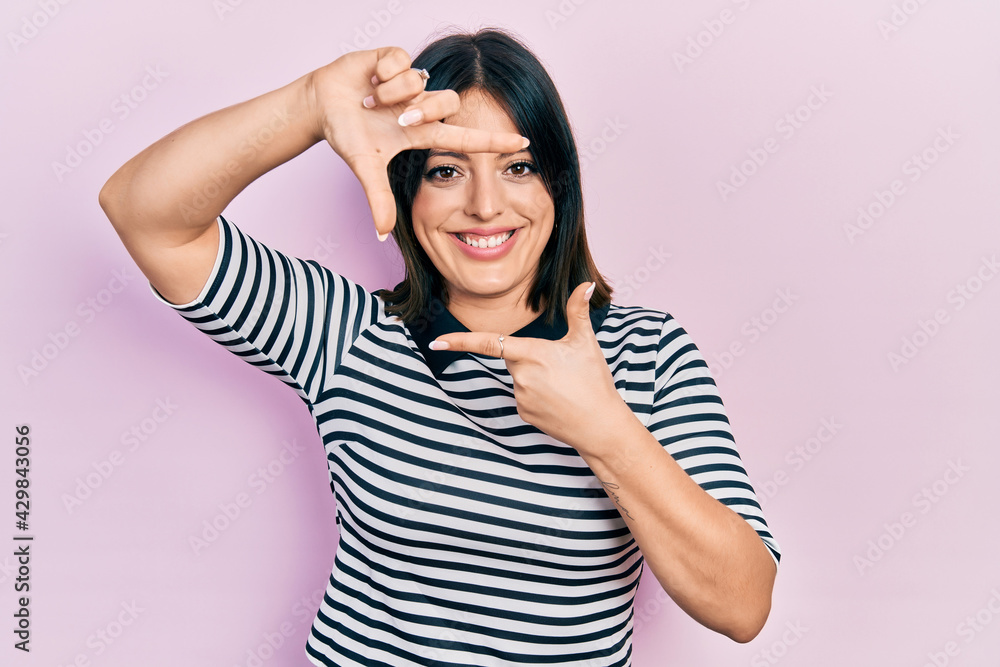 Young hispanic woman wearing casual clothes smiling making frame with hands and fingers with happy face. creativity and photography concept. Young hispanic woman wearing casual clothes smiling making frame with hands and fingers with happy face. creativity and photography concept.
