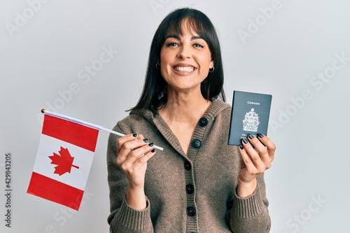 Photography Young hispanic woman holding canada flag and passport smiling with a happy and cool smile on face