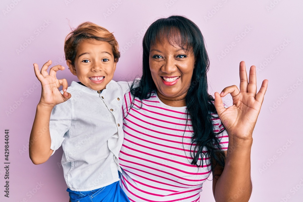 Hispanic family of mother and son hugging together with love doing ok sign with fingers, smiling friendly gesturing excellent symbol Hispanic family of mother and son hugging together with love doing ok sign with fingers, smiling friendly gesturing excellent symbol