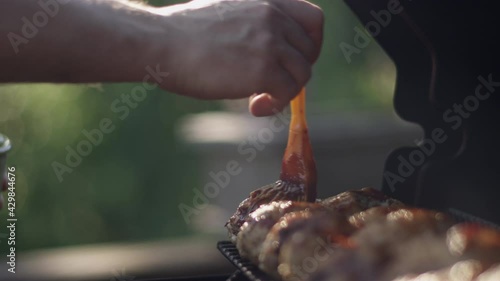 Dad brushes plenty of bbq sauce on the grilled chicken