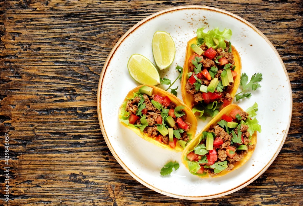 Mexican tacos with roast minced meat with corn and black beans, onions, fresh tomatoes, paprika and cilantro are flavored with guacamole sauce. top view. Mexican tacos with roast minced meat with corn and black beans, onions, fresh tomatoes, paprika and cilantro are flavored with guacamole sauce. top view.