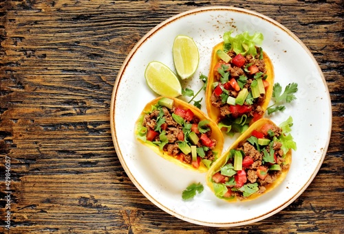 Mexican tacos with roast minced meat with corn and black beans, onions, fresh tomatoes, paprika and cilantro are flavored with guacamole sauce. top view.