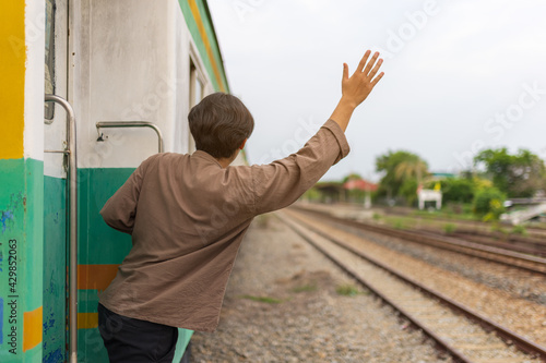 Handsome Young Asian man hand to say hello or goodbye to friend on train, Waving Goodbye photo