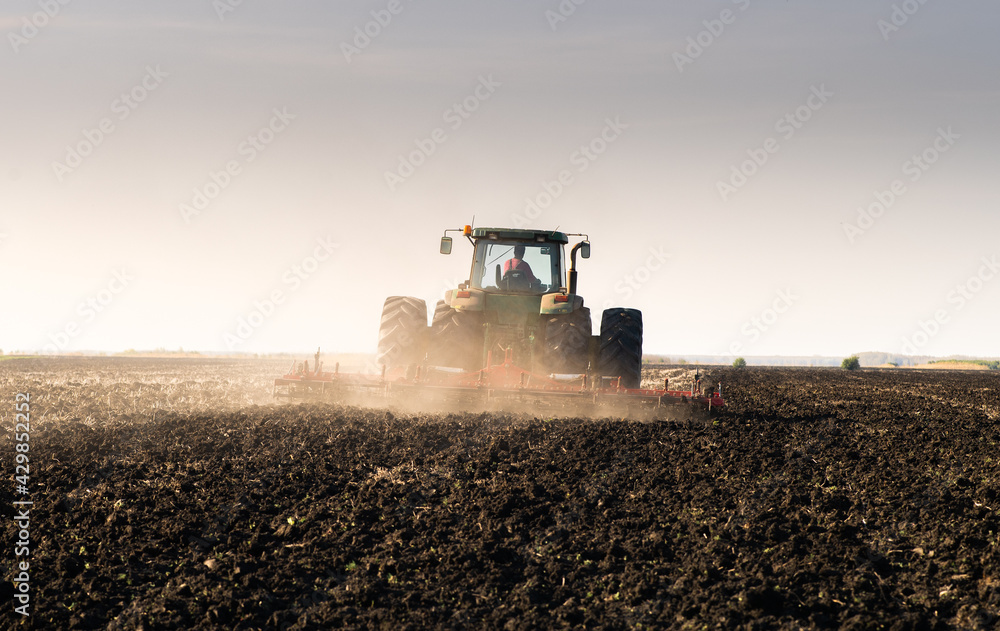 Fototapeta premium Tractor is preparing the land at dusk