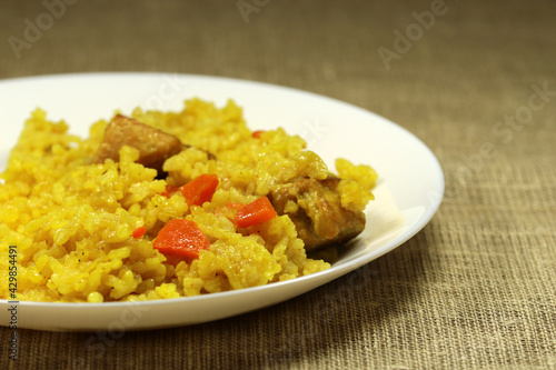 Traditional asian dish - pilaf from rice, vegetables and meat in a white plate. Selective focus.