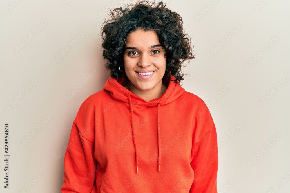 Fototapeta premium Young hispanic woman with curly hair wearing casual sweatshirt with a happy and cool smile on face. lucky person.