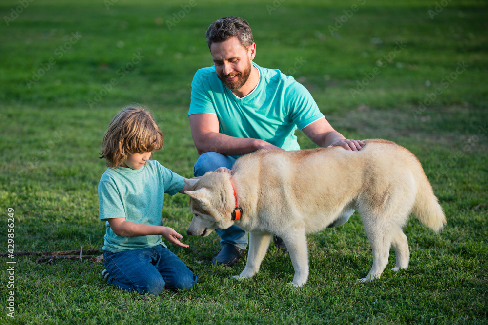Obraz premium Smiling Father and Son with Pet. Happy Family with Loyal Pedigree Dog have Fun at the Backyard.
