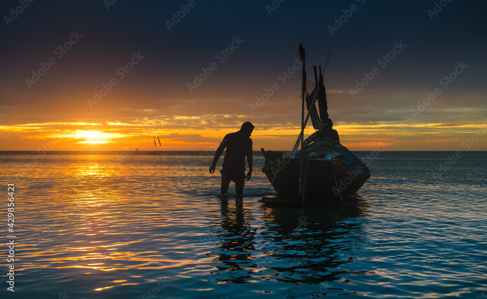 Silhouette of working fisherman and wooden boat.