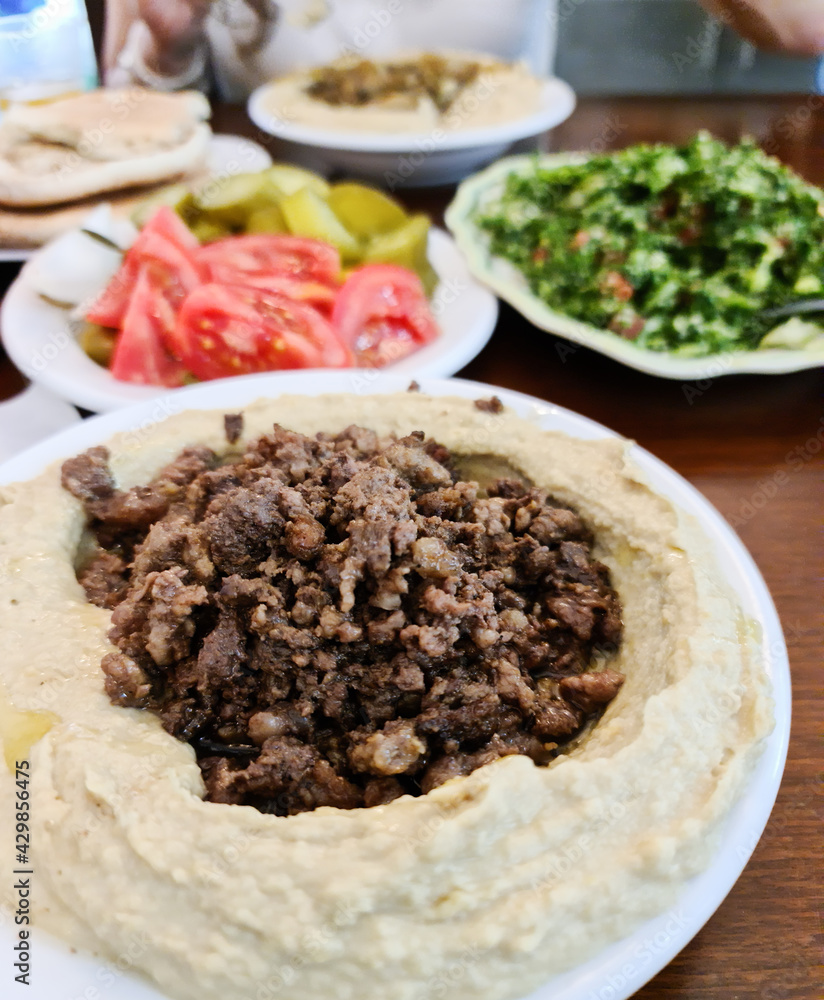 Creamy hummus with spicy mutton minced meat in clay bowl on stone background. Ramadan food. Creamy hummus with spicy mutton minced meat in clay bowl on stone background. Ramadan food.