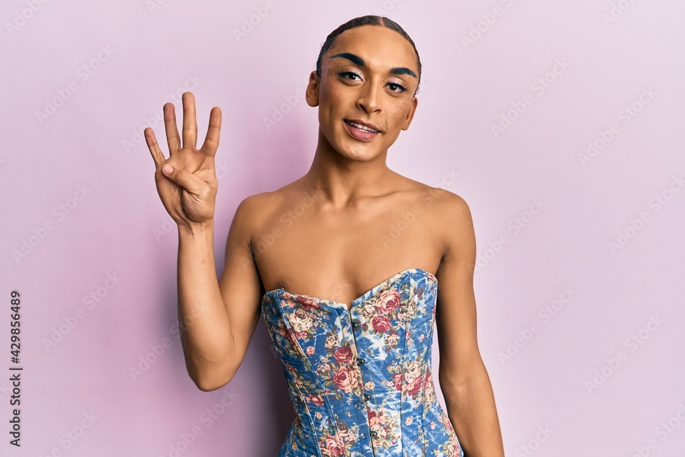 Hispanic man wearing make up and long hair wearing elegant corset showing and pointing up with fingers number four while smiling confident and happy. Hispanic man wearing make up and long hair wearing elegant corset showing and pointing up with fingers number four while smiling confident and happy.
