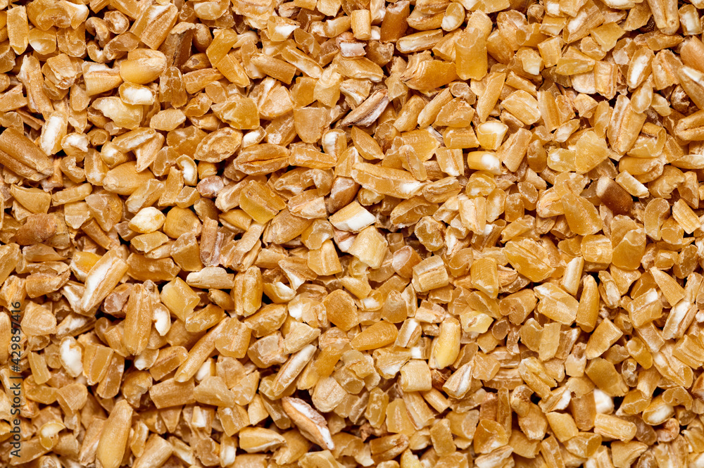 Background texture of fine ground brown bulgur made from cracked durum wheat or cereal groats rich in protein and dietary fiber for a healthy whole grain ingredient Background texture of fine ground brown bulgur made from cracked durum wheat or cereal groats rich in protein and dietary fiber for a healthy whole grain ingredient