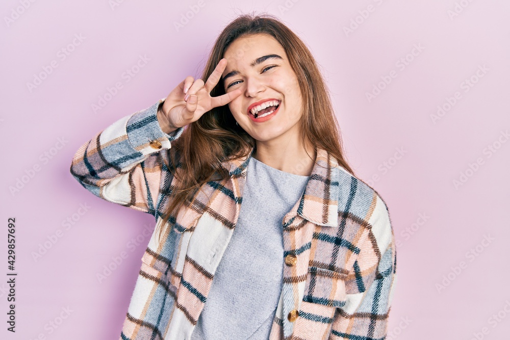 Young caucasian girl wearing casual clothes doing peace symbol with fingers over face, smiling cheerful showing victory Young caucasian girl wearing casual clothes doing peace symbol with fingers over face, smiling cheerful showing victory