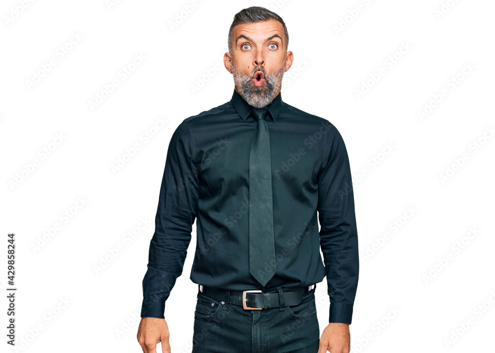 Fototapeta premium Middle age handsome man wearing business clothes scared and amazed with open mouth for surprise, disbelief face