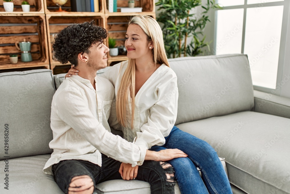 Obraz premium Young couple sitting on the sofa hugging at home.