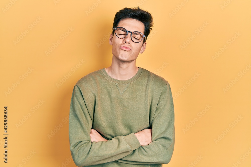 Young hispanic man with arms crossed gesture looking at the camera blowing a kiss being lovely and sexy. love expression. Young hispanic man with arms crossed gesture looking at the camera blowing a kiss being lovely and sexy. love expression.