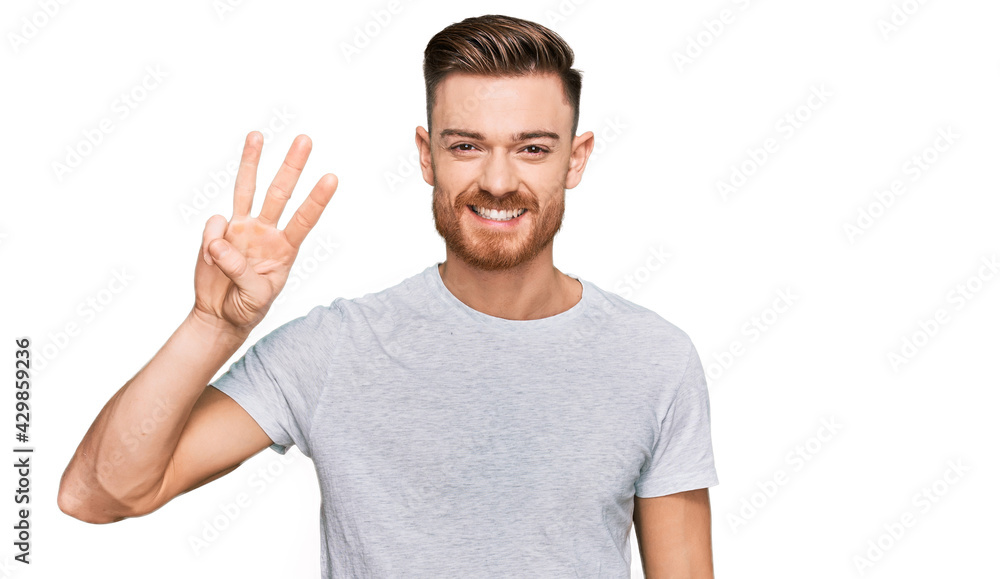Naklejka premium Young redhead man wearing casual grey t shirt showing and pointing up with fingers number three while smiling confident and happy.