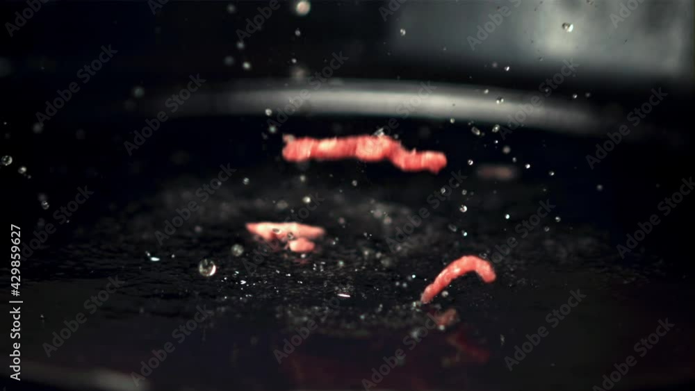 Super slow motion of mince falls on the pan with splashes of oil. Filmed on a high-speed camera at 1000 fps.On a black background. Super slow motion of mince falls on the pan with splashes of oil. Filmed on a high-speed camera at 1000 fps.On a black background.