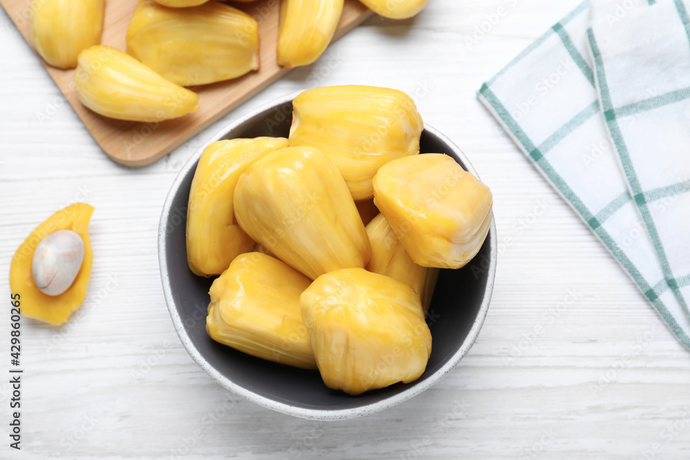 Delicious exotic jackfruit bulbs on white wooden table, flat lay