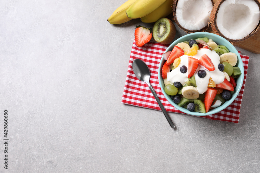 Delicious fruit salad on grey table, flat lay. Space for text
