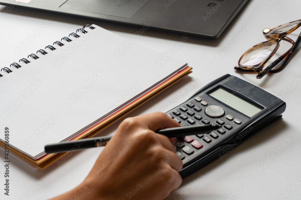 A woman's hand using calculator on the office desk. Accounting, stock market concept. A woman's hand using calculator on the office desk. Accounting, stock market concept.