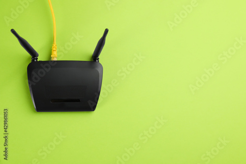 Modern Wi-Fi router on green background, top view. Space for text