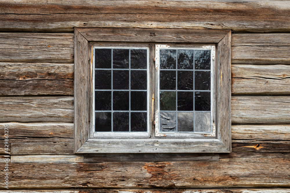 Old window with handmade glas panes on a 200 years old wooden log cottage. Natural aged wood surfaces Old window with handmade glas panes on a 200 years old wooden log cottage. Natural aged wood surfaces