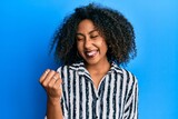 Beautiful african american woman with afro hair wearing casual clothes celebrating surprised and amazed for success with arms raised and eyes closed