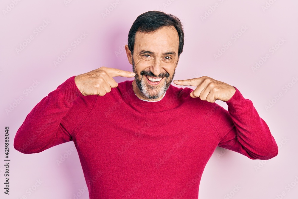Middle age hispanic man wearing casual clothes smiling cheerful showing and pointing with fingers teeth and mouth. dental health concept. Middle age hispanic man wearing casual clothes smiling cheerful showing and pointing with fingers teeth and mouth. dental health concept.
