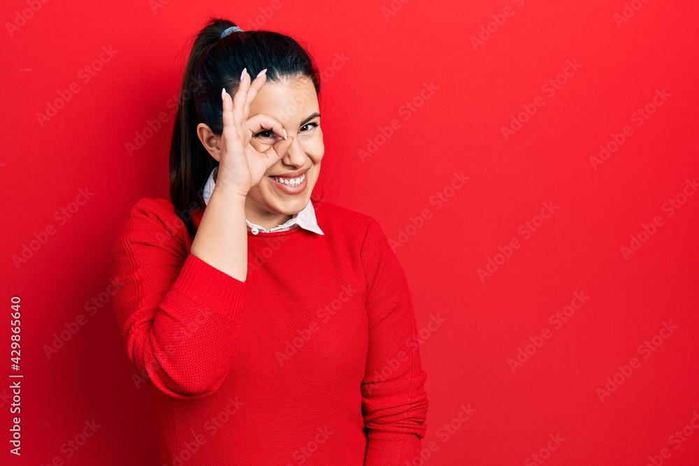 Young hispanic woman wearing casual clothes smiling happy doing ok sign with hand on eye looking through fingers Young hispanic woman wearing casual clothes smiling happy doing ok sign with hand on eye looking through fingers