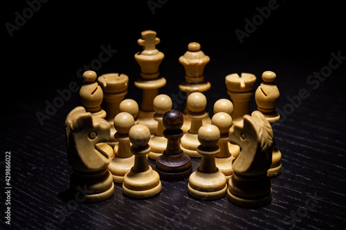Todas las piezas blancas rodean a un peón negro sobre un tablero negro
