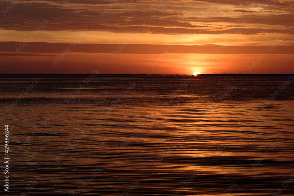 Sunset sun over ocean water. Natural sky colors. Sunrise seascape.