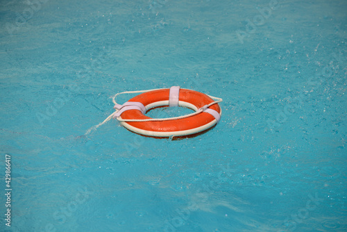 No swimming. Water rescue emergency equipment. Rescue ring floating in clear pool water. Summer.