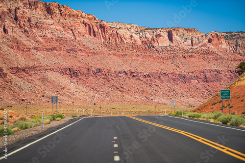 Landscape with orange rocks, sky with clouds and asphalt road in summer. American roadtrip.