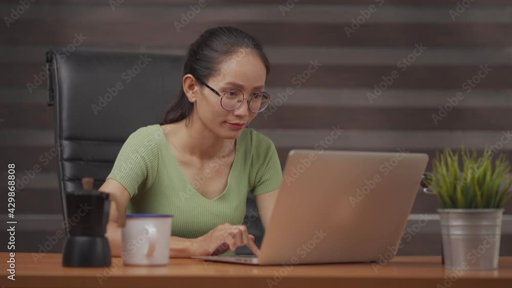 Young Asian freelancer woman working on computer at home. Casual concentrated entrepreneur developing new project while working on laptop at home. Young Asian freelancer woman working on computer at home. Casual concentrated entrepreneur developing new project while working on laptop at home.