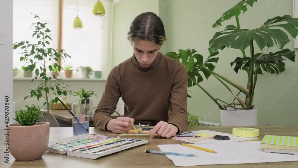 Teenager boy painting at home with watercolors. Creativity, hobby, teens concept Teenager boy painting at home with watercolors. Creativity, hobby, teens concept