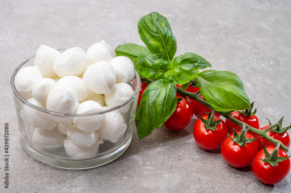 Italian tricolore, small balls of fresh white soft Italian mozzarella cheese, ripe red cherry tomatoes and fresh green basil herb, ready for making caprese salad Italian tricolore, small balls of fresh white soft Italian mozzarella cheese, ripe red cherry tomatoes and fresh green basil herb, ready for making caprese salad