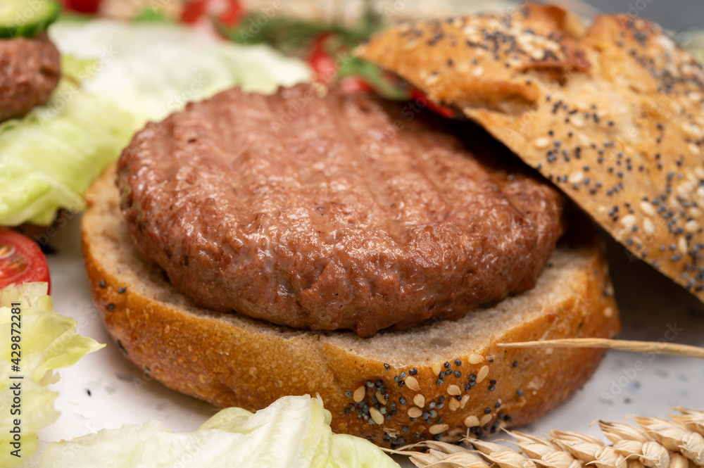 Making tasty vegetarian vegan hamburger from plant based soya beans burger, organic bun with seeds and fresh vegetables Making tasty vegetarian vegan hamburger from plant based soya beans burger, organic bun with seeds and fresh vegetables