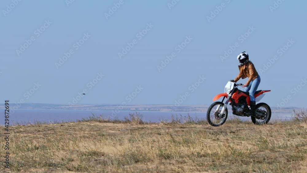 A girl on a motocross motorcycle rides near a cliff over the lake, slow motion video. Training before a motocross competition. A girl on a motocross motorcycle rides near a cliff over the lake, slow motion video. Training before a motocross competition.