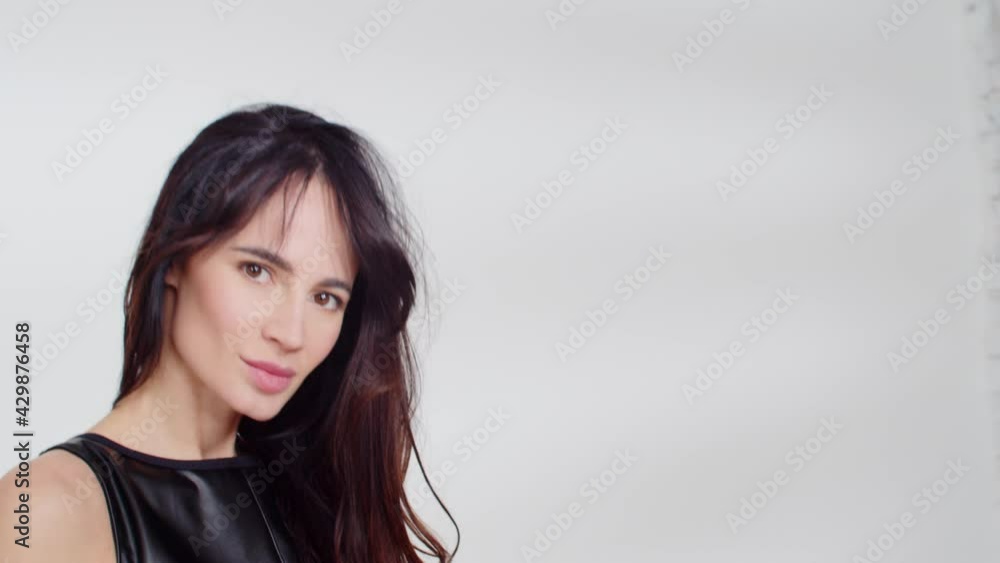 Attractive woman posing in a black two-piece swimsuit in the studio. Young beautiful girl on a white background. The model with long hair. 4K vertical video Attractive woman posing in a black two-piece swimsuit in the studio. Young beautiful girl on a white background. The model with long hair. 4K vertical video