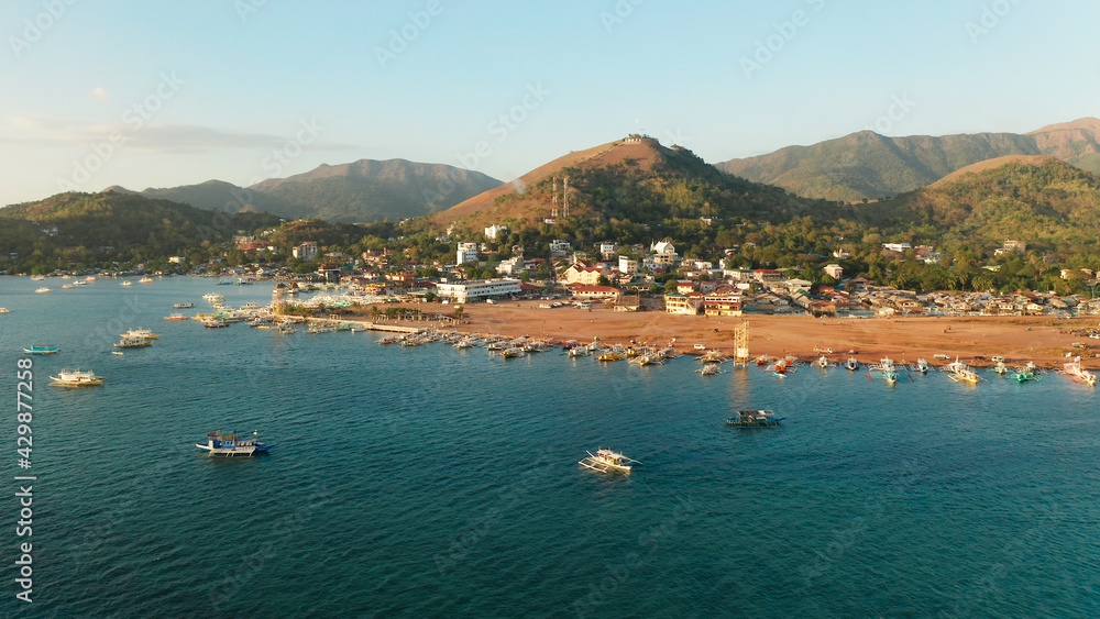 aerial view Pier and promenade Coron town with boats on Busuanga island. Wooden boats waiting at pier. Seascape with mountains. Philippines, Palawan