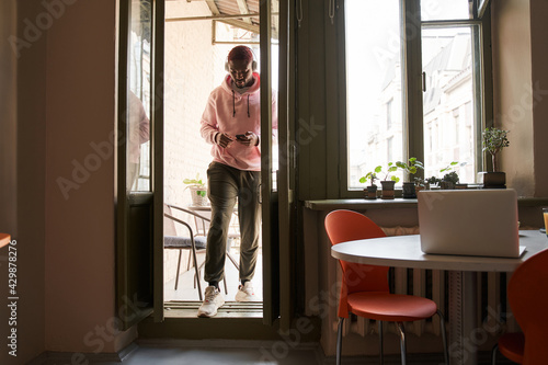 Man wearing headset entering to the kitchen from the balcony after the morning relax