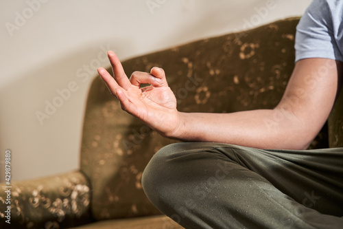 Man holding hand at the mudras gesture while sitting in yoga posture and meditating