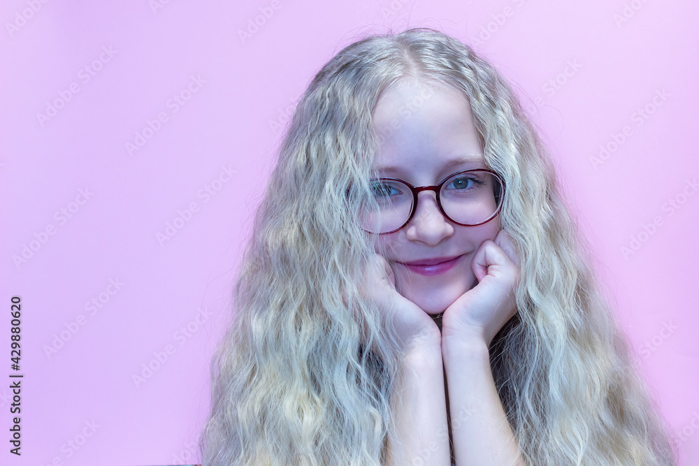 Portrait of a beautiful teenage girl in red glasses with blonde swirling hair.