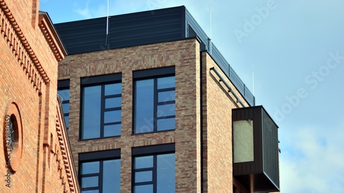 Modern brick and glass facade of the office building.  A contrasting combination of sky and brick texture on a building. Architectural facade of a red brick building..