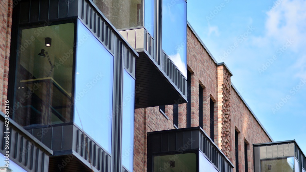 Modern brick and glass facade of the office building.  A contrasting combination of sky and brick texture on a building. Architectural facade of a red brick building..