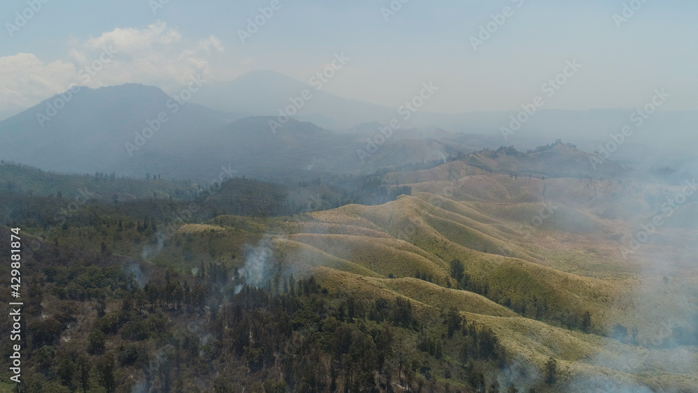 aerial view forest fire smoke on slopes hills. wild fire in tropical forest, Java Indonesia. natural disaster fire in Southeast Asia